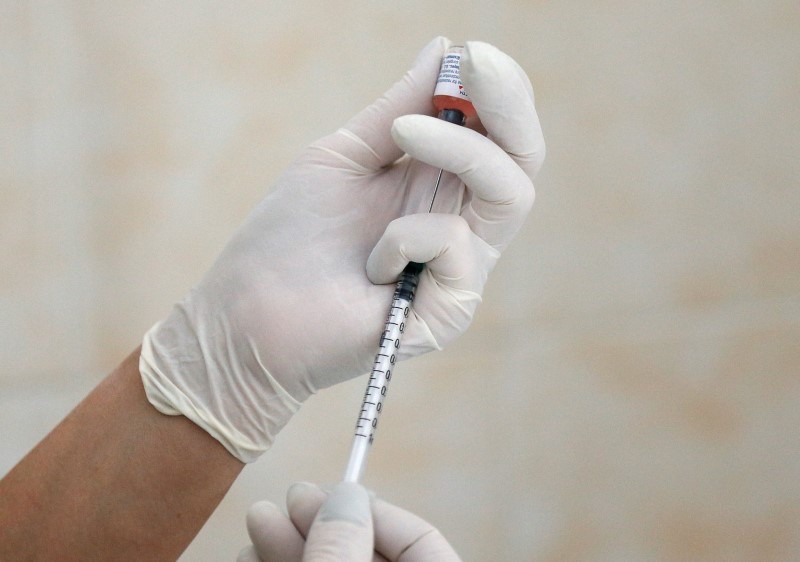 A nurse fills a syringe with a vaccine before administering an injection at a children's clinic in Kiev