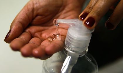 Mulher colocando álcool em gel na mão