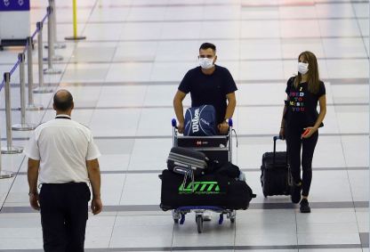 Passageiros com máscaras de proteção contra coronavírus caminham no Aeroporto In