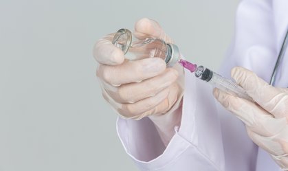 Médico de luvas colocando líquido em uma seringa