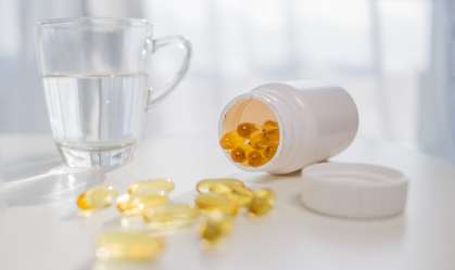 Xícara com água ao lado que pote de cápsulas de vitamina D