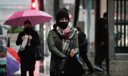 Pedestres se protegem do frio e da chuva na Avenida Paulista, em SP