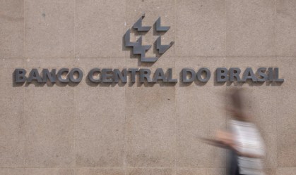 Pessoa caminha em frente a letreiro do Banco Central do Brasil