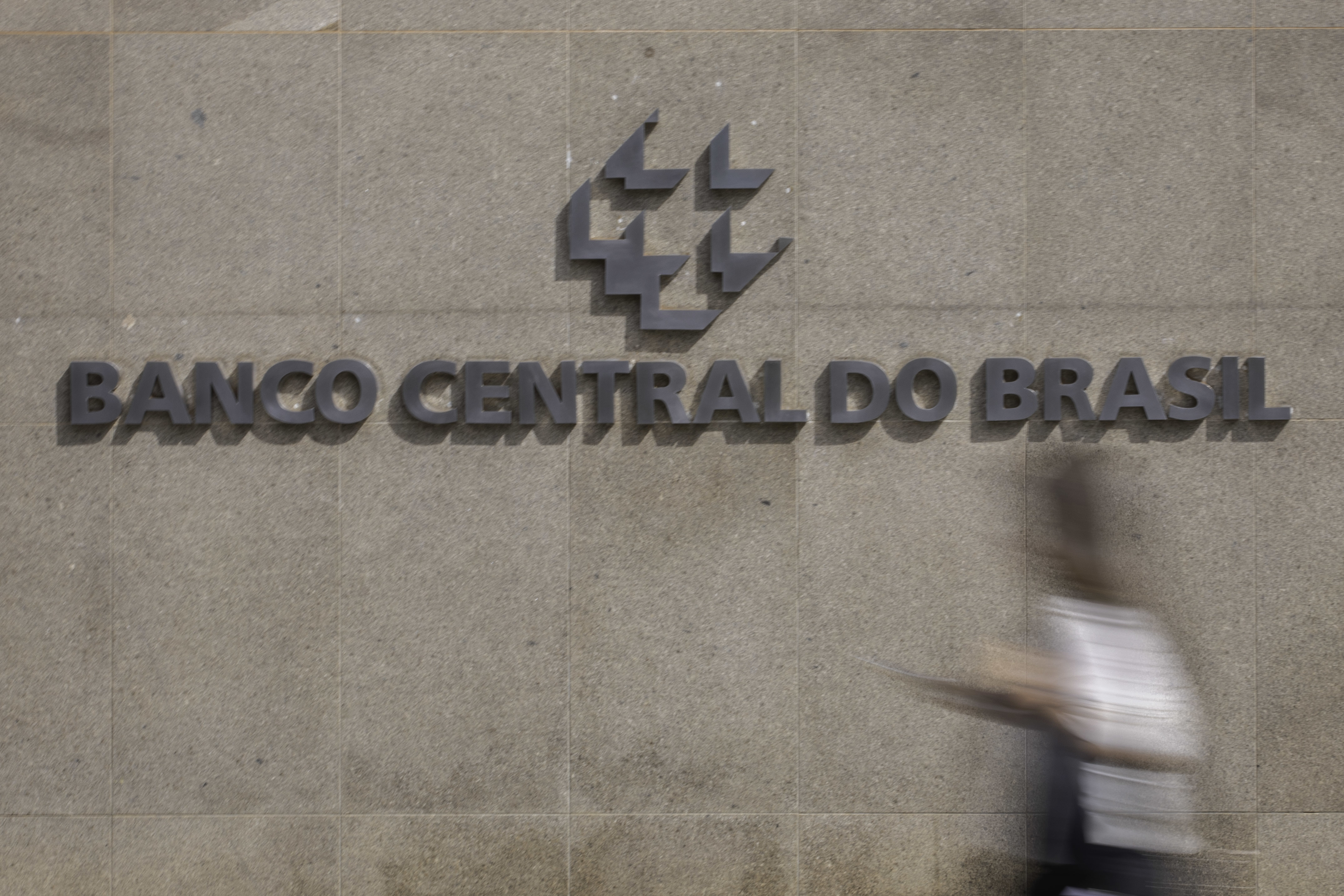 Pessoa caminha em frente a letreiro do Banco Central