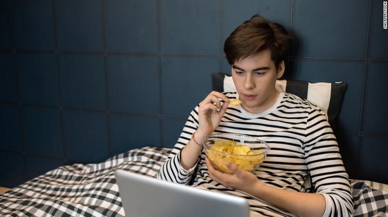 Homem vendo algo no computador comendo salgadinho