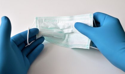 Mãos com luvas segurando máscara