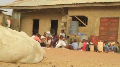 Meninos sentados em frente a casa tendo aula