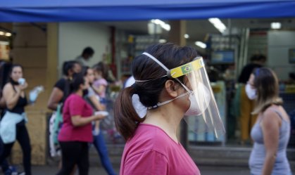 Pedestre usa máscara  e face shield ao andar pela 25 de março