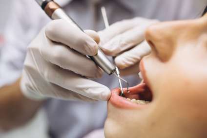 Dentista usando ferramenta na boca de paciente