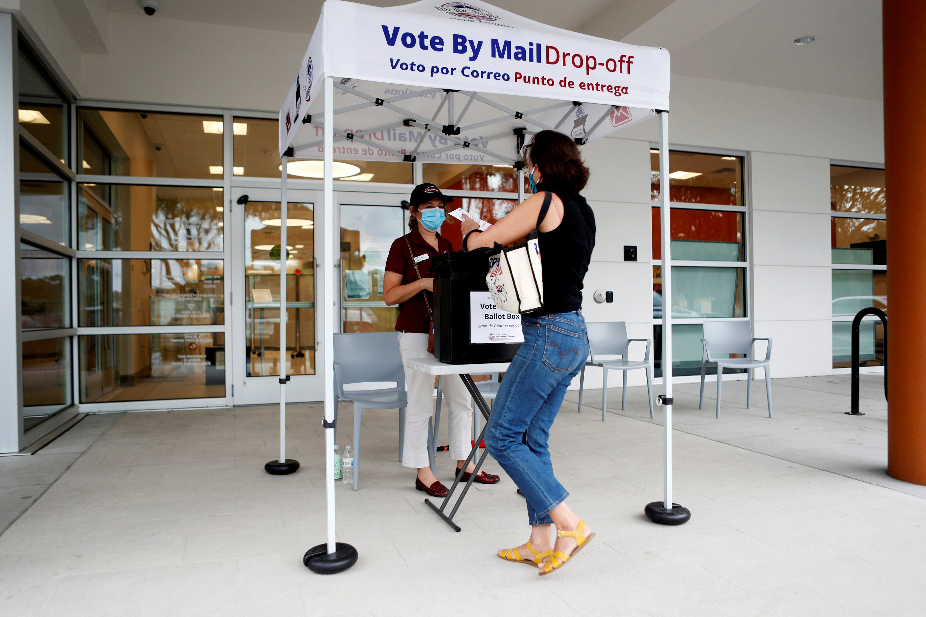 Pessoa depositando seu voto adiantado em ponto de coleta