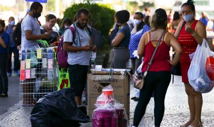 Pessoas com e sem máscara em comércio de rua em Brasília