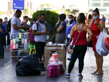 Pessoas com e sem máscara em comércio de rua em Brasília