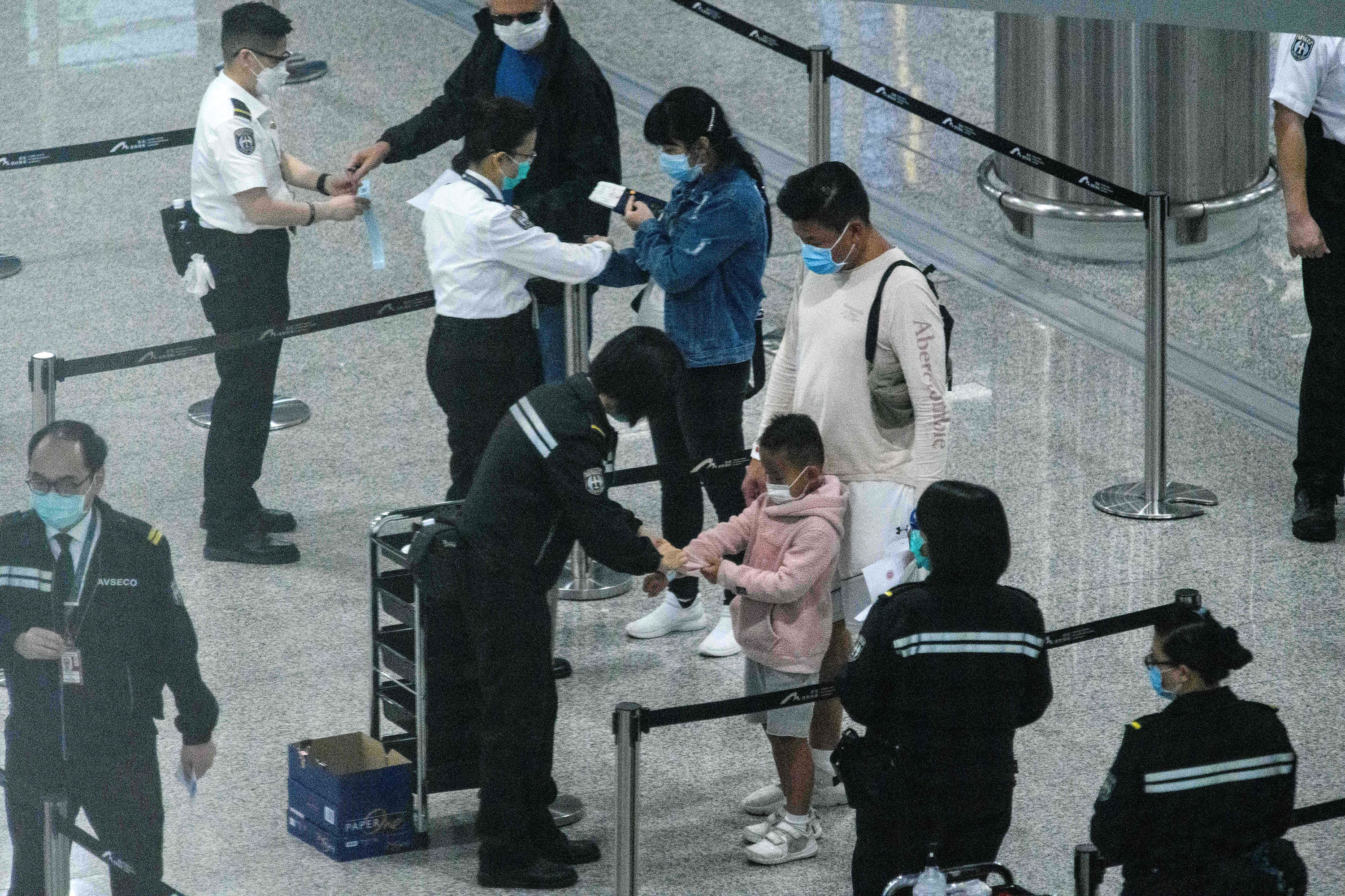 Oficiais colocam pulseiras de monitoramento em viajantes chegando à Hong Kong