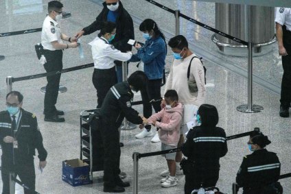 Oficiais colocam pulseiras de monitoramento em viajantes chegando à Hong Kong