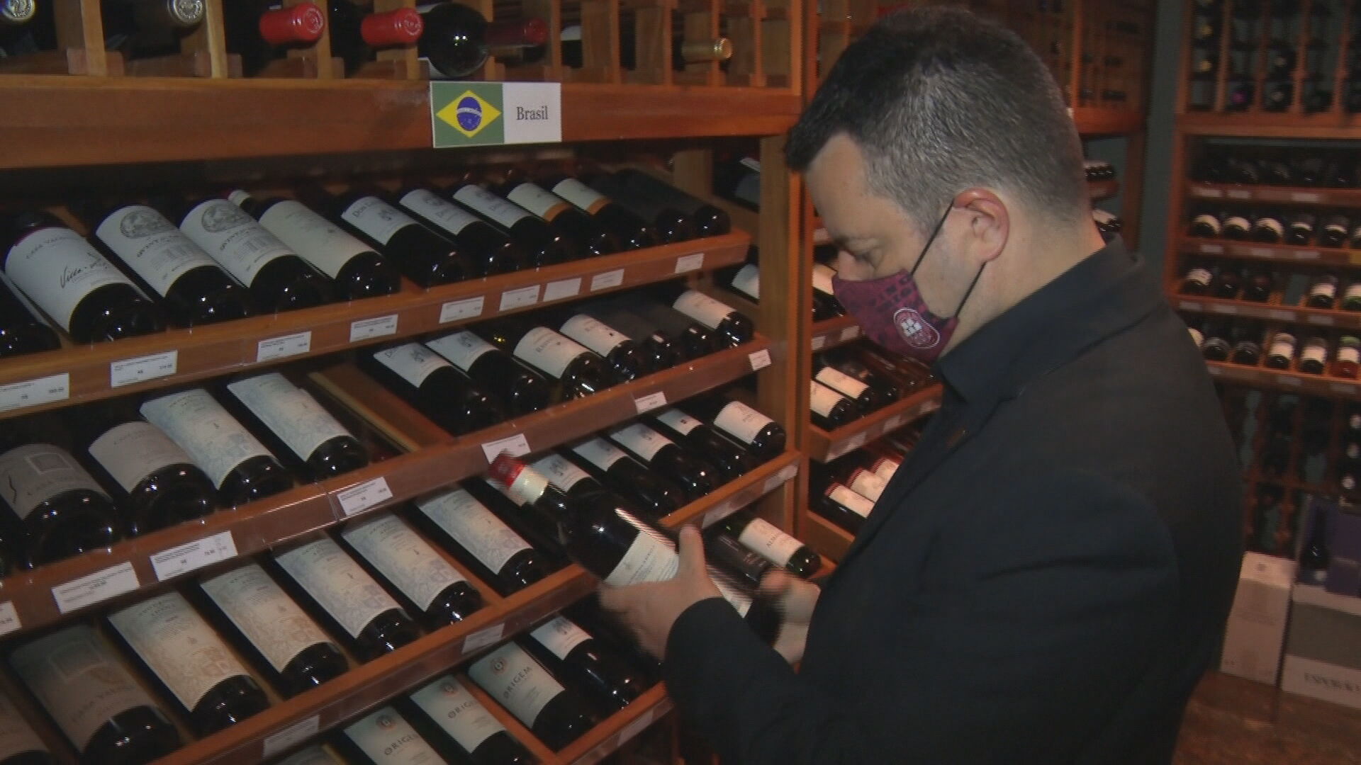Homem olha rótulo de garrafa de vinho
