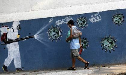 Homem de máscara passa por grafite do coronavírus no Rio de Janeiro