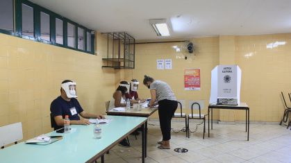 Mesários equipados com face shield em local de votação