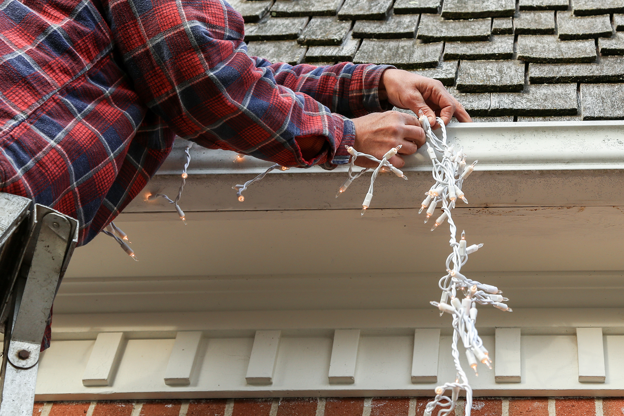 Homem decora casa com luzes de Natal