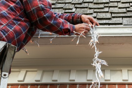 Homem decora casa com luzes de Natal