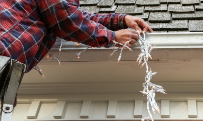 Homem decora casa com luzes de Natal