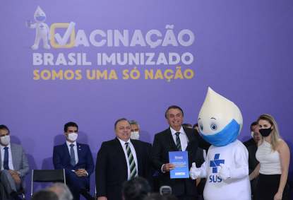 O presidente da República, Jair Bolsonaro (c) abraça o mascote Zè Gotinha