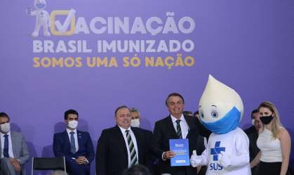 O presidente da República, Jair Bolsonaro (c) abraça o mascote Zè Gotinha 