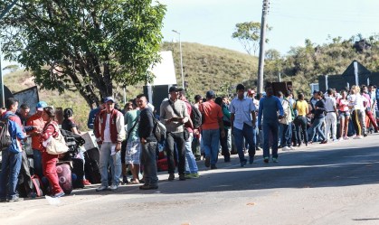 Imigrantes venezuelanos cruzam a pé a fronteira entre Venezuela e Brasil