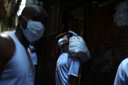 Voluntário carrega doações para moradores da favela da Rocinha, no RJ