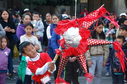 Criança quebra piñata em celebração do Dia de Reis no México