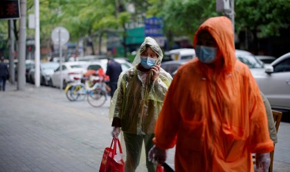 Pessoas com máscaras de proteção caminham em rua de Wuhan, na China