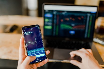 Pessoa segura celular e acompanha investimentos
