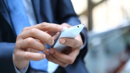 Homem de terno mexendo no celular