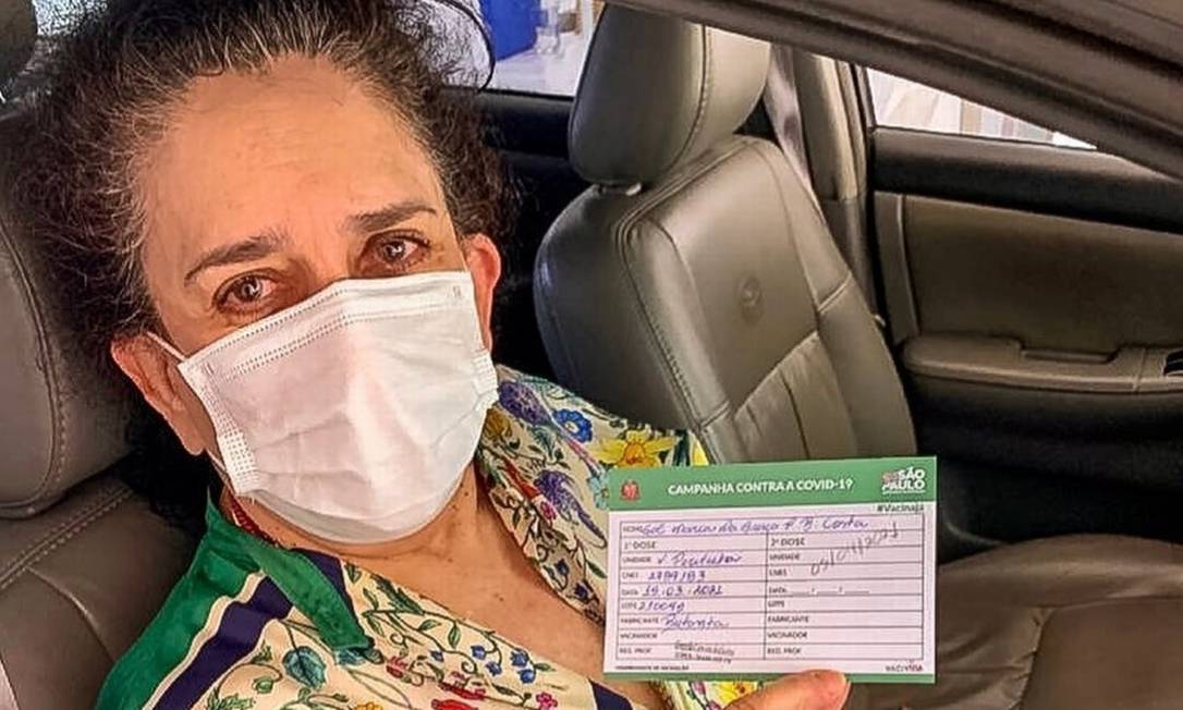 A cantora Gal Costa posa com o cartão de vacinação em mãos