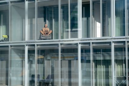 Homem toma sol da janela do apartamento, vitamina D
