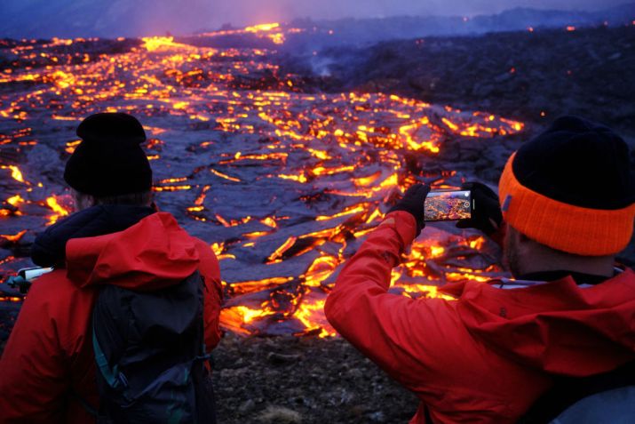 Turistas tiram foto perto da crosta escaldante de magma expelida por vulcão na Península de Reykjanes, na Islândia / Foto: Anton Brink - 21.mar.2021/Anadolu Agency via Getty Images