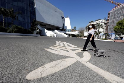 Pedestre passeia com cachorro sobre símbolo da Palma de Ouro, em Cannes, França