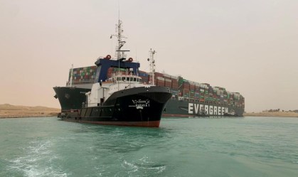 Rebocador trabalha para tentar desencalhar porta-contêineres no Canal de Suez