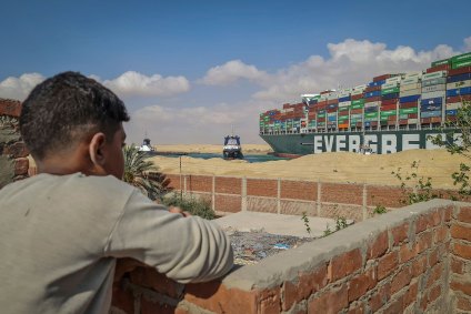 Garoto observa rebocadores tentarem desencalhar navio no canal de Suez