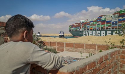 Garoto observa rebocadores tentarem desencalhar navio no canal de Suez