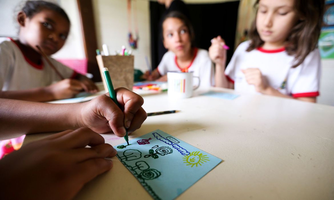 Crianças fazem desenho durante aula na escola