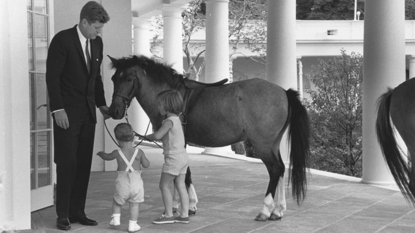 No lado de fora do Salão Oval, o presidente John F. Kennedy e seus filhos John e Caroline, brincam com o pônei Macaroni em 22 de junho de 1962 / Photoquest/Getty Images