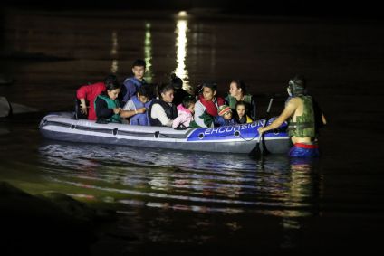 Imigrantes cruzando de barco o Rio Grande