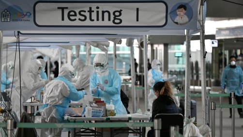 Médicos usam roupa de proteção para coletar teste de coronavírus em aeroporto
