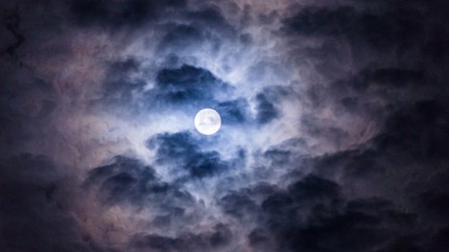 Na foto, lua cheia entre as nuvens no Guarujá, no litoral de São Paulo