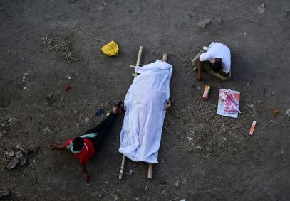 Covid-19: Parentes sentam-se ao lado do corpo de um membro da família na Índia