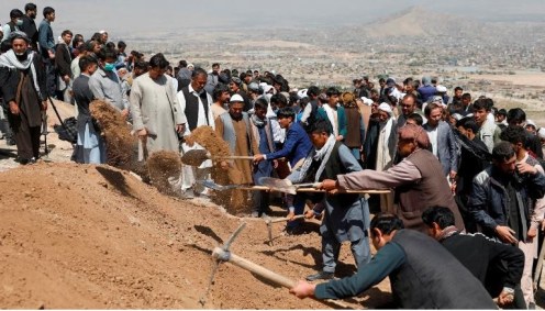 Homens cavam sepulturas para as vítimas da explosão no sábado no Afeganistão