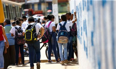 Crianças e adolescentes conversam em frente a uma escola