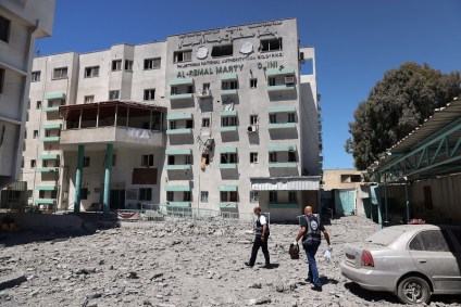 Médicos palestinos caminham na sede do Ministério da Saúde destruída após ataque