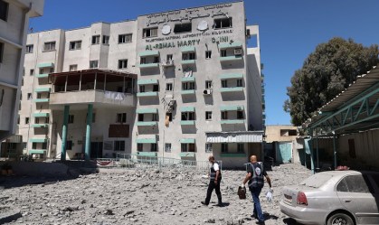 Médicos palestinos caminham na sede do Ministério da Saúde destruída após ataque