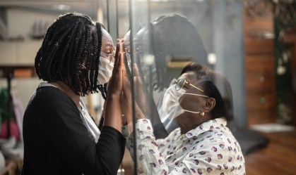 Pessoas se vendo por um vidro, de máscaras